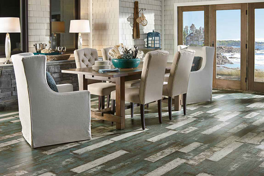 Dining room with a wood table that mixes numerous types of chairs on grey washed wood floors.