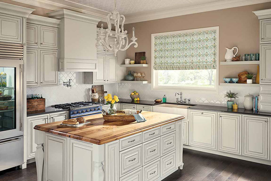 A kitchen with white cabinets and tile backsplash, an island with a wood countertop on hardwood floors.